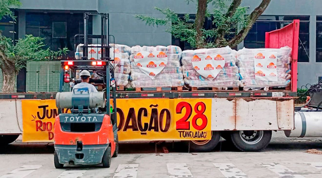 Colaborador da loja Assaí Curitiba Kennedy controlando uma empilhadeira com alimentos que serão depositados em uma carreta com doações para as vítimas das enchentes no Rio Grande do Sul